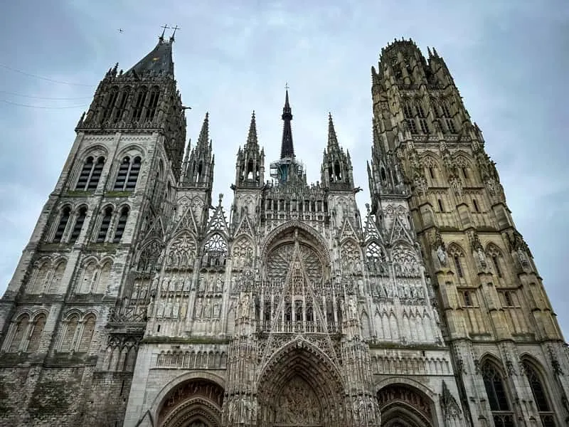 Guide showing the medieval old town and cathedral spire on a Joan of Arc rouen cathedral tour in Rouen, France